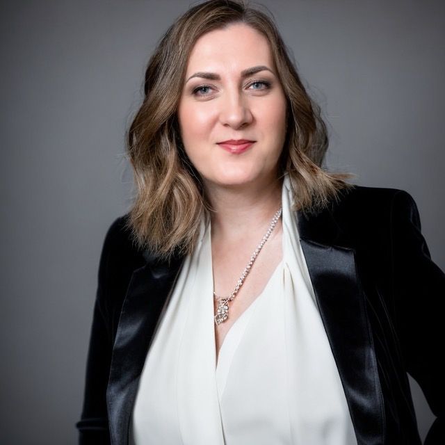 Ales Blake, author — a woman with shoulder-length brown hair wearing a black blazer and white blouse